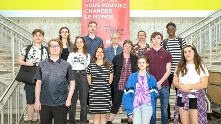 Des élèves avec leur enseignante au bas des escaliers du puits du hall