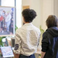 Des gens qui assistent à un exposition d'un projet en photographie à la bibliothèque