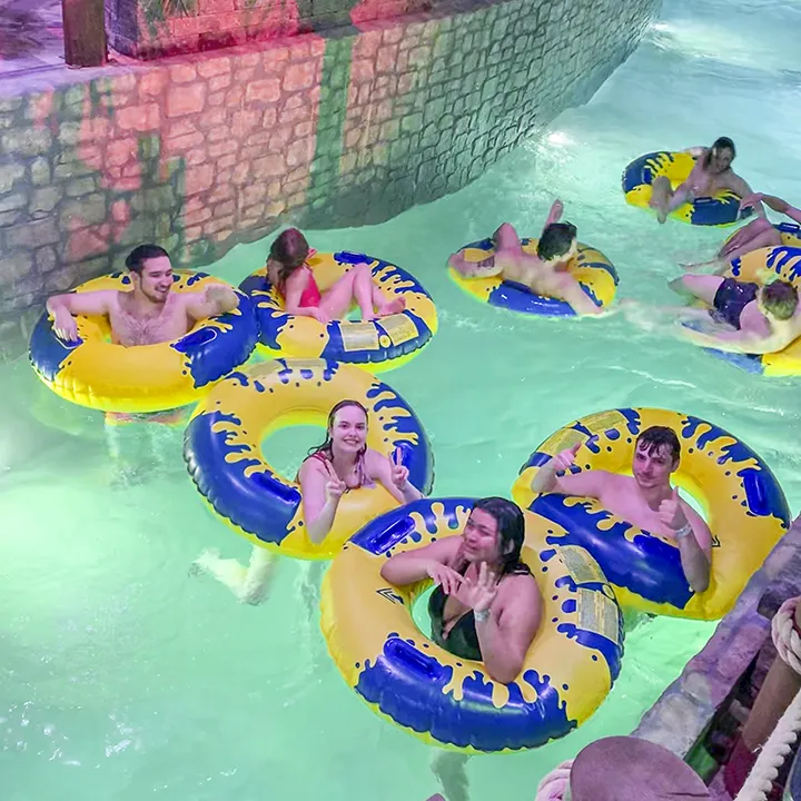 Un groupe d'étudiantes et d'étudiants en maillots de bain profitent d'une descente en bouées lors de vacances au village Valcartier dans l'eau couleur turquoise d'un parc aquatique extérieur.