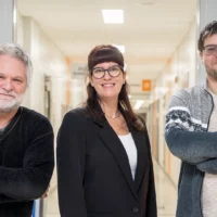 Dans le corridor du cégep, les trois personnes qui forment le jury de Cégeps en spectacle prennent la pose pour une photo.