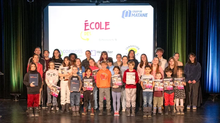 Des élèves du primaire, en compagnie de leurs mentors du cégep, prennent la pose dans le cadre de la remise de leur diplôme de l'École des Grands, sur la scène de l'auditorium du cégep.