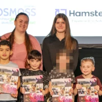 Des élèves du primaire, en compagnie de leurs mentors du cégep, prennent la pose dans le cadre de la remise de leur diplôme de l'École des Grands, sur la scène de l'auditorium du cégep.