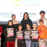 Des élèves du primaire, en compagnie de leurs mentors du cégep, prennent la pose dans le cadre de la remise de leur diplôme de l'École des Grands, sur la scène de l'auditorium du cégep.