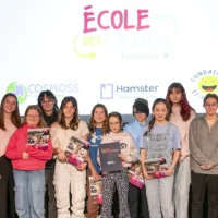 Des élèves du primaire, en compagnie de leurs mentors du cégep, prennent la pose dans le cadre de la remise de leur diplôme de l'École des Grands, sur la scène de l'auditorium du cégep.